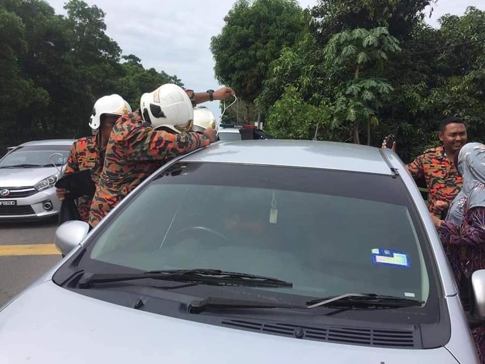 Firemen improvising to unlock the car. — Facebook/Kopiah Kau Senget