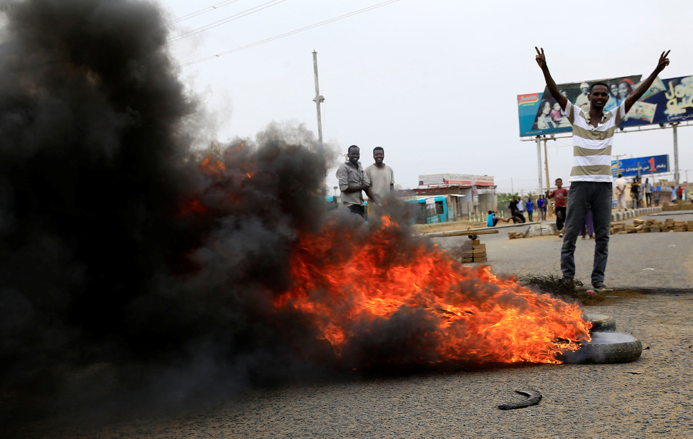 A Sudanese protester gestures near burning tyres used to erect a barricade on a street, demanding that the country's Transitional Military Council handover power to civilians, in Khartoum June 4, 2019. u00e2u20acu201d Reuters/Stringer pic