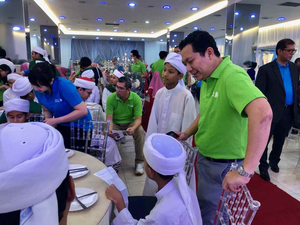 Standard Chartered Saadiq chief executive officer Mohd Suhaimi Abdul Hamid (standing, in green) checking in with one of the kids during the financial education session. — Picture courtesy of Standard Chartered Bank Malaysia