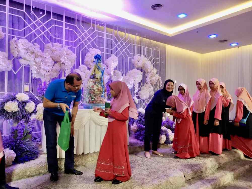 Standard Chartered Bank Malaysia human resources country head Rahmat Hashim (left, in blue) and brand, sponsorship, and sustainability head Mastura Adnan (right, in black) handing out goodie bags to the children from Rumah Baitul Hidayah. — Picture courtesy of Standard Chartered Bank Malaysia