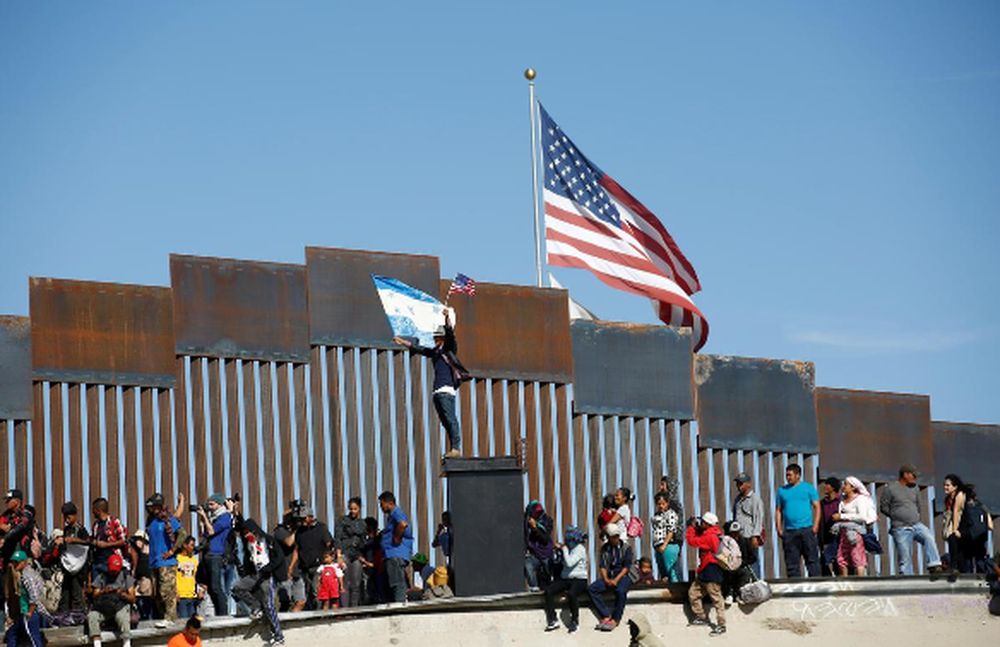 A migrant, part of a caravan of thousands travelling from Central America en route to the United States, holds flags of Honduras and the United States in front of the border wall in Tijuana, Mexico November 25, 2018. u00e2u20acu201d Reuters pic