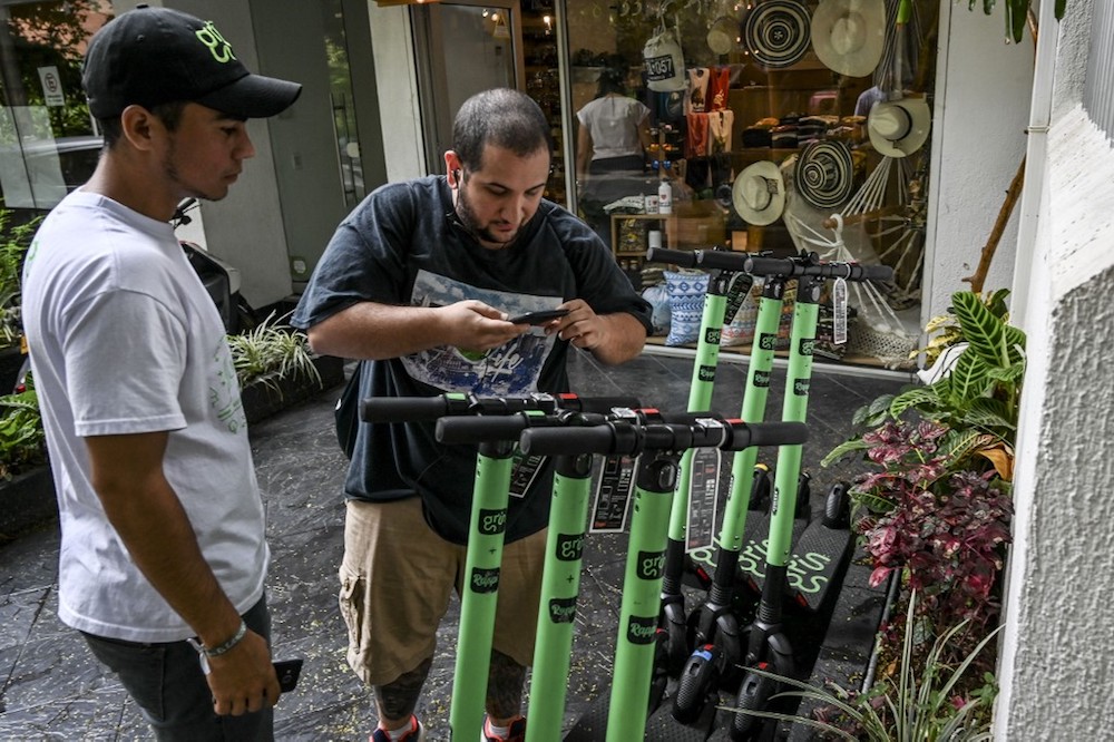 A man scans the code of an electric scooter with his cell phone in Medellin, Antioquia department, Colombia, July 3, 2019. — AFP pic