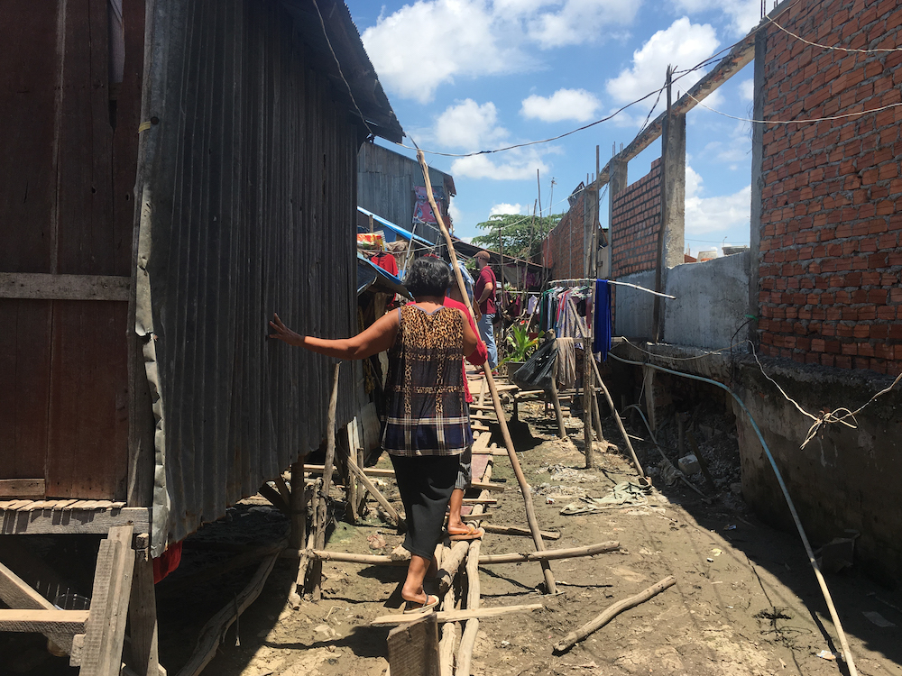 A woman walks on a makeshift bridge of wooden planks and poles in an informal settlement at the edge of Boeung Tompoun in Phnom Penh May 27, 2019. u00e2u20acu201d Thomson Reuters Foundation/Rina Chandran pic