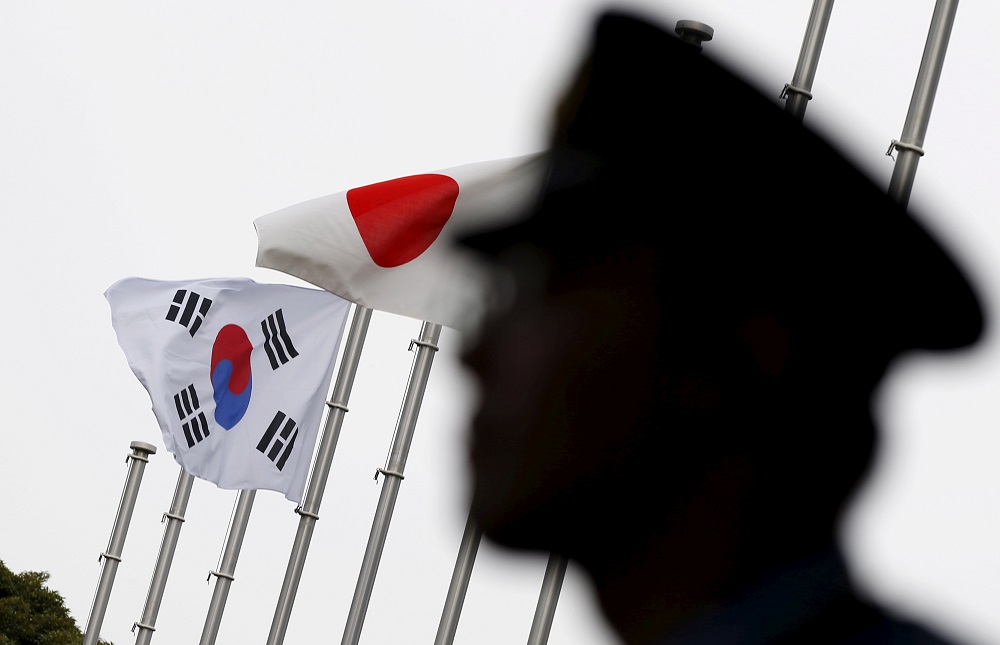 A police officer stands guard near Japan and South Korea national flags at hotel, where South Korean embassy in Japan is holding the reception to mark the 50th anniversary of normalisation of ties, Tokyo June 22, 2015. u00e2u20acu201d Reuters pic