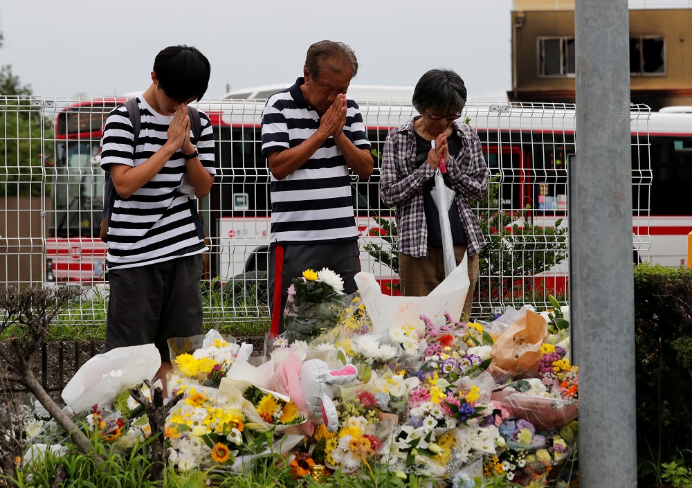 People pray in front of a row bouquets placed out for victims of the torched Kyoto Animation building in Kyoto July 20, 2019. u00e2u20acu201d Reuters pic