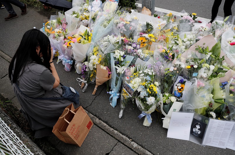 A woman prays in front of a row of flowers placed for victims of the torched Kyoto Animation building in Kyoto July 20, 2019. u00e2u20acu201d Reuters pic