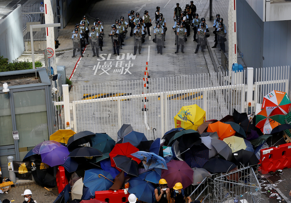 Anti-extradition bill protesters use umbrellas to build a barricade while riot police stand guard on the Legislative Council compound  in Hong Kong July 1, 2019. u00e2u20acu201d Reuters picnn