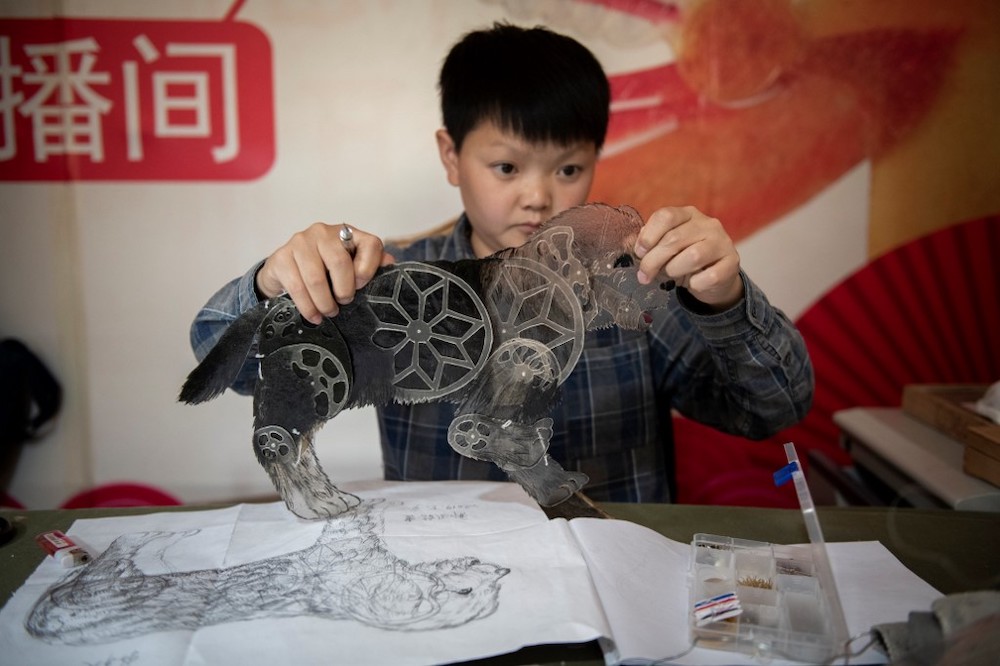 In this picture taken on May 9, 2019, Jin Xinchun, a member of the Flying Dragon Troupe, creates a shadow puppet at the troupe's studio on the outskirts of Beijing. u00e2u20acu201d AFP picnn