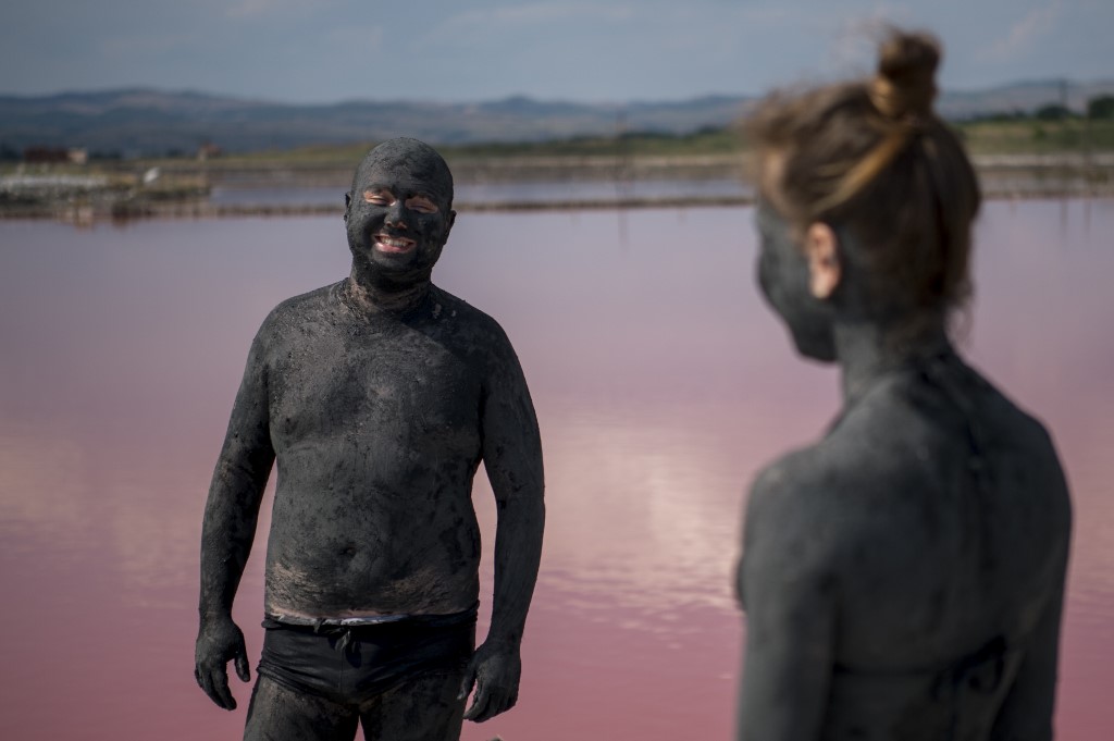 A couple covered in mud wait for it to dry at the Salt-works lakes near the Black Sea town of Burgas in Bulgaria on July 25, 2019. u00e2u20acu201d AFP pic