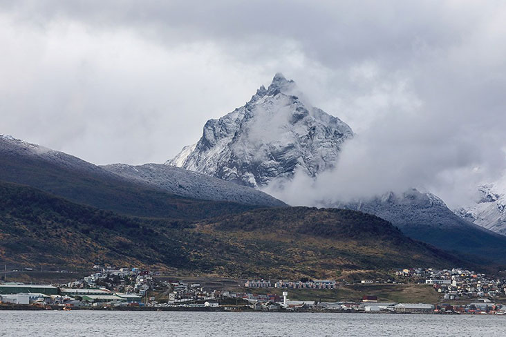 The city of Ushuaia with a dramatic background of mountains and white clouds.