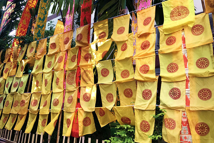 A wall of yellow Dharmacakra (meaning “Wheel of Dharma”) flags with red Thammachak wheels.