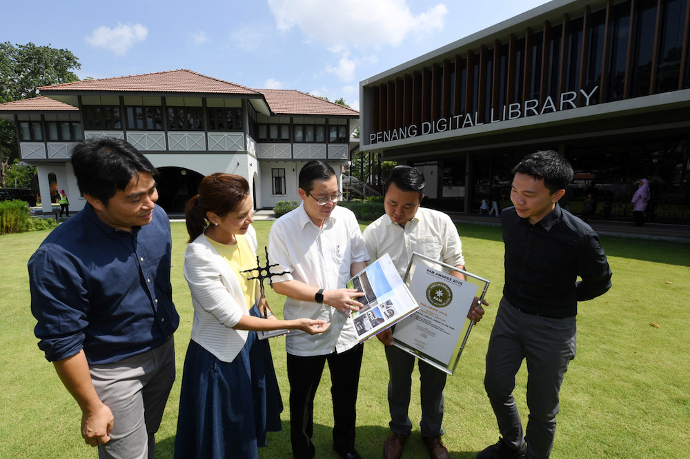 Principal project architect of the Penang Digital Library Tan Bee Eu (2nd left) shares details of the Malaysian Institute of Architects gold medal award with Lim Guan Eng in George Town July 6, 2019. u00e2u20acu201d Bernama pic