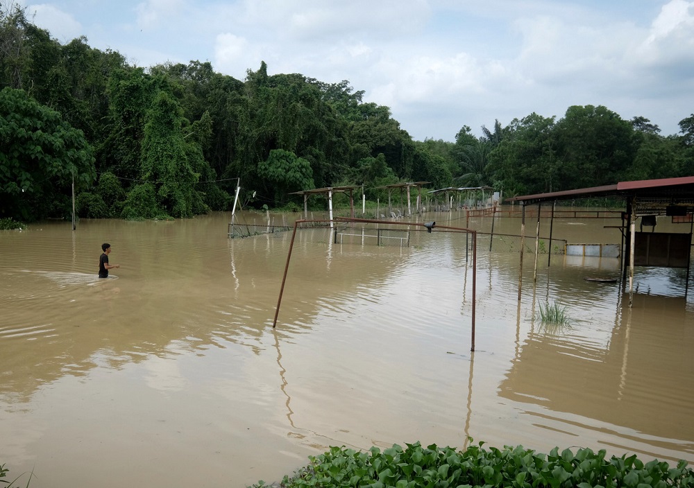 Seorang remaja terpaksa meredah air sedalam kira-kira satu metre untuk ke kawasan gerainya yang telah ditenggelami air akibat banjir kilat dekat Melaka Pindah di Alor Gajah 7 Julai, 2019. u00e2u20acu201d Foto Bernama