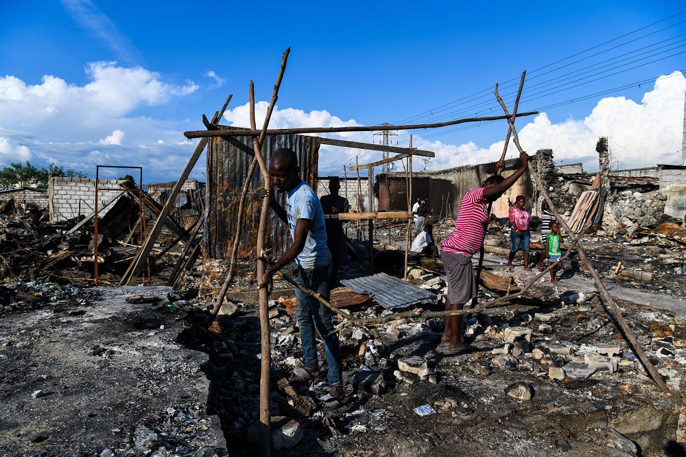 A man and a woman repair their house, which they say was burned down by the gangs, in a slum in the Haitian capital Port-au-Prince April 23, 2019. u00e2u20acu201d AFP pic       
