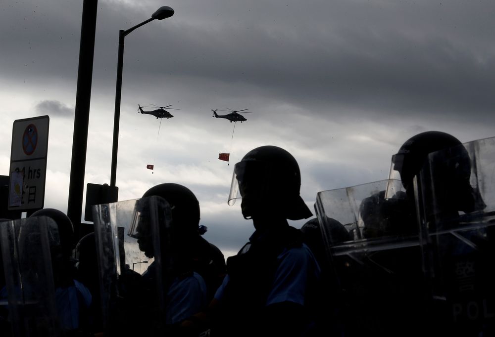 Helicopters fly the national flags of Hong Kong and China above riot police and protesters during the anniversary of Hong Kongu00e2u20acu2122s handover to China in Hong Kong, China, July 1, 2019. u00e2u20acu201d Reuters file