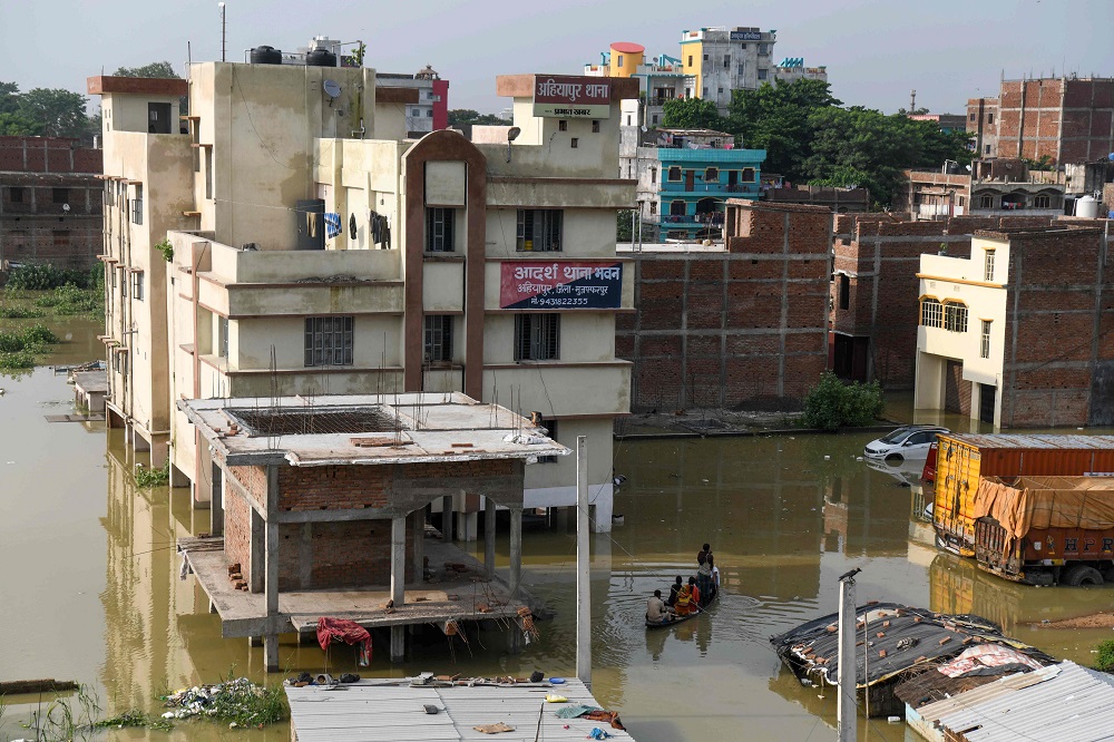 An Indian policeman travels with residents on a wooden boat to cross a flooded locality near the Ahiyapur police station at Muzaffarpur district in the Indian state of Bihar July 18, 2019. u00e2u20acu201d AFP pic            