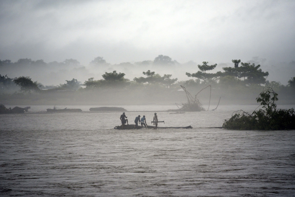 In this picture taken July 15, 2019, Indian men catch a tree in the flooded Manas river, following heavy rainfall in Baksa district of Assam, in the North-Eastern states of India. u00e2u20acu201d AFP pic 