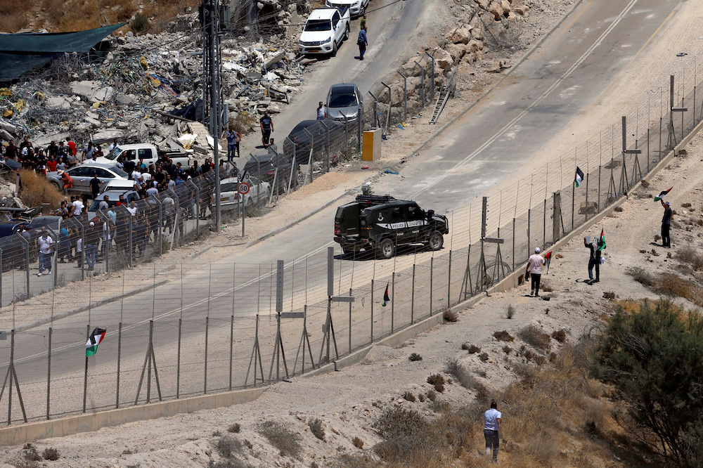 Palestinian demonstrators protest against the Israeli demolitions of Palestinian homes as an Israeli police vehicle is seen, in the village of Sur Baher which sits on either side of the Israeli barrier in East Jerusalem and the Israeli-occupied West Bank 