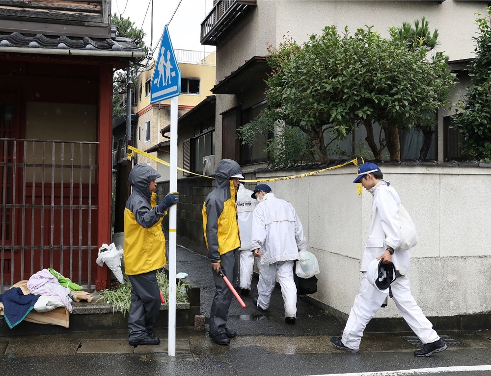 Police officers move towards the Kyoto Animation company studio wwhich was set on fire killing at least two dozen people in Kyoto on July 19, 2019. — Photo by Jiji Press via AFP
