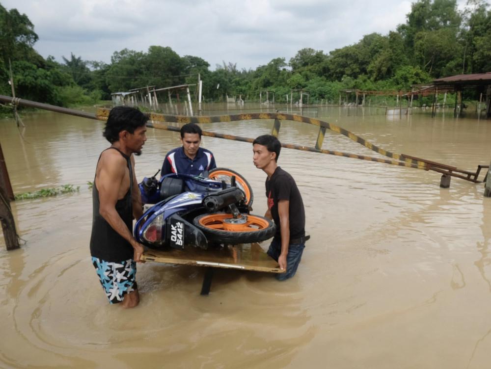 Three men remove a motorcycle from flood waters at Melaka Pindah, July 7, 2019. u00e2u20acu201d Bernama picn