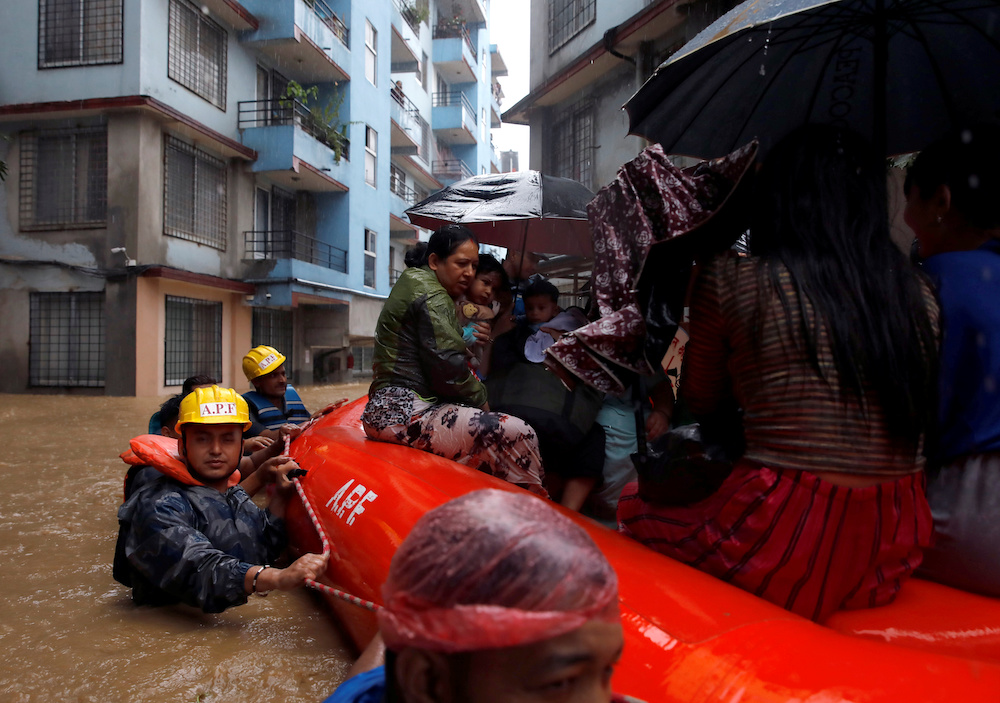 A woman carrying a child is moved by rescue workers towards dry ground from a flooded colony in Kathmandu, Nepal July 12, 2019. u00e2u20acu201d Reuters pic