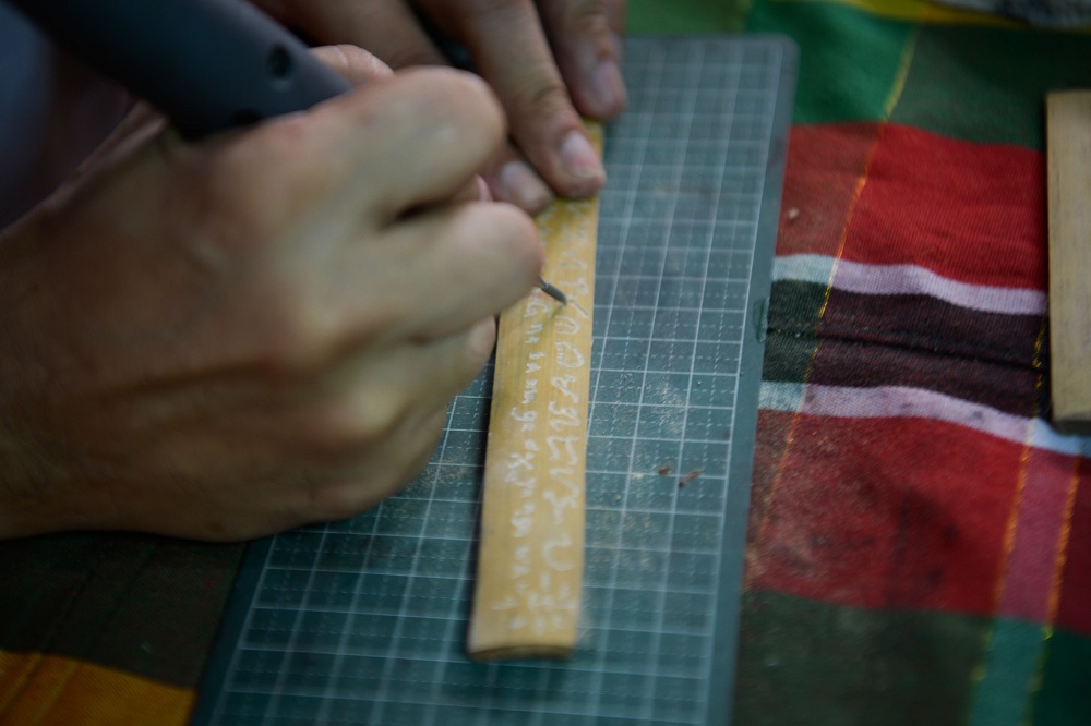 This photo taken on June 11, 2019 shows cultural advocate Leo Emmanuel Castro inscribing indigenous Baybayin script onto a piece of bamboo at his shop in Manila. — AFP pic