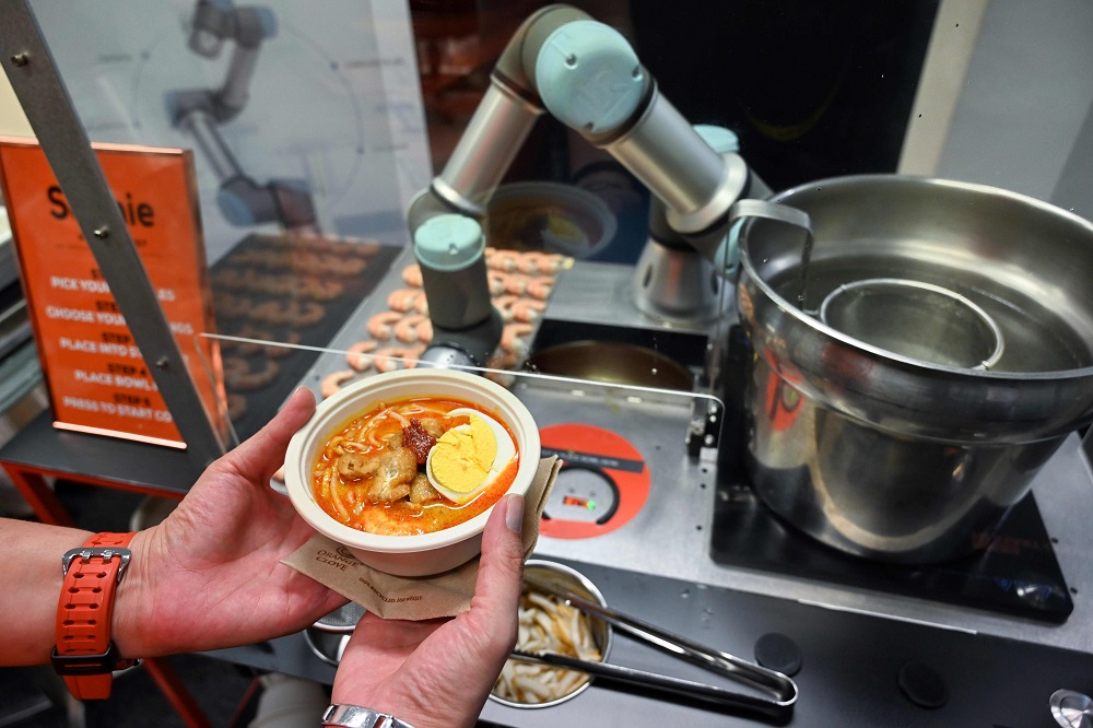 This picture taken on July 26, 2019 shows a person holding a bowl of laksa, a local dish of rice noodles served in a curry sauce, after it was prepared by Sophie the robotic chef in Singapore. — AFP pic