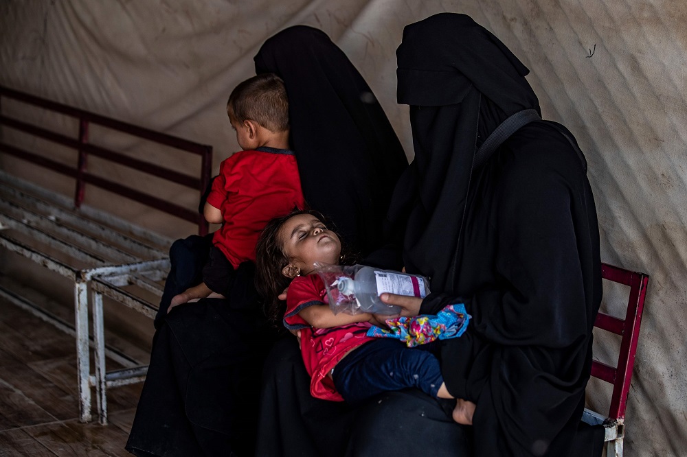 Displaced Syrian mothers hold their children as they wait outside a clinic at al-Hol camp for the internally displaced people in al-Hasakeh governorate in northeastern Syria July 23, 2019. — AFP pic      