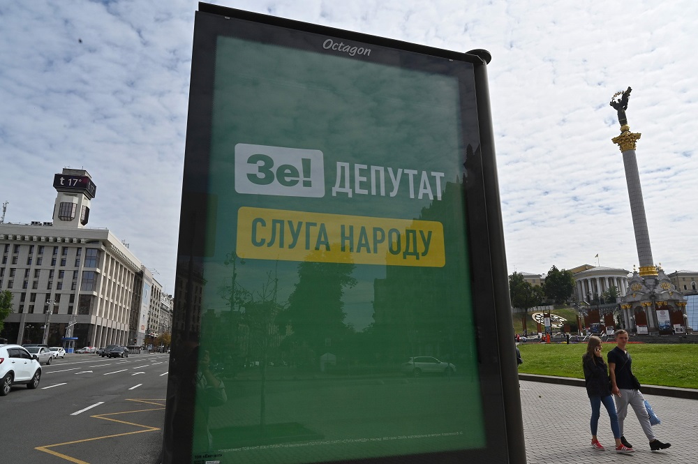 People walk past a billboard depicting the logo of Ukrainian President Volodymyr Zelensky and with slogan reading u00e2u20acu02dcZe deputy is servant of the peopleu00e2u20acu2122 set at Independence Square in Kiev on July 12, 2019. u00e2u20acu201d AFP pic            