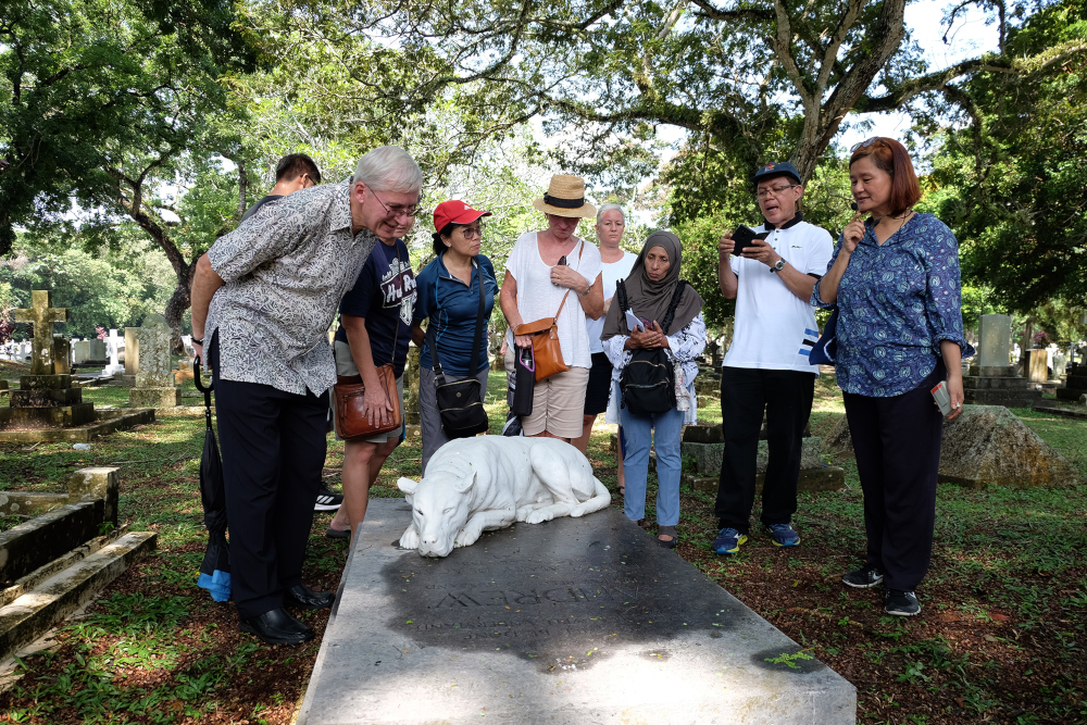 PHT Vice President Khoo Salma Nasution (right) telling visitors about the dog sculpture on Andrew Duncan's grave at the cemetery. u00e2u20acu201d Picture by Steven Ooi KE
