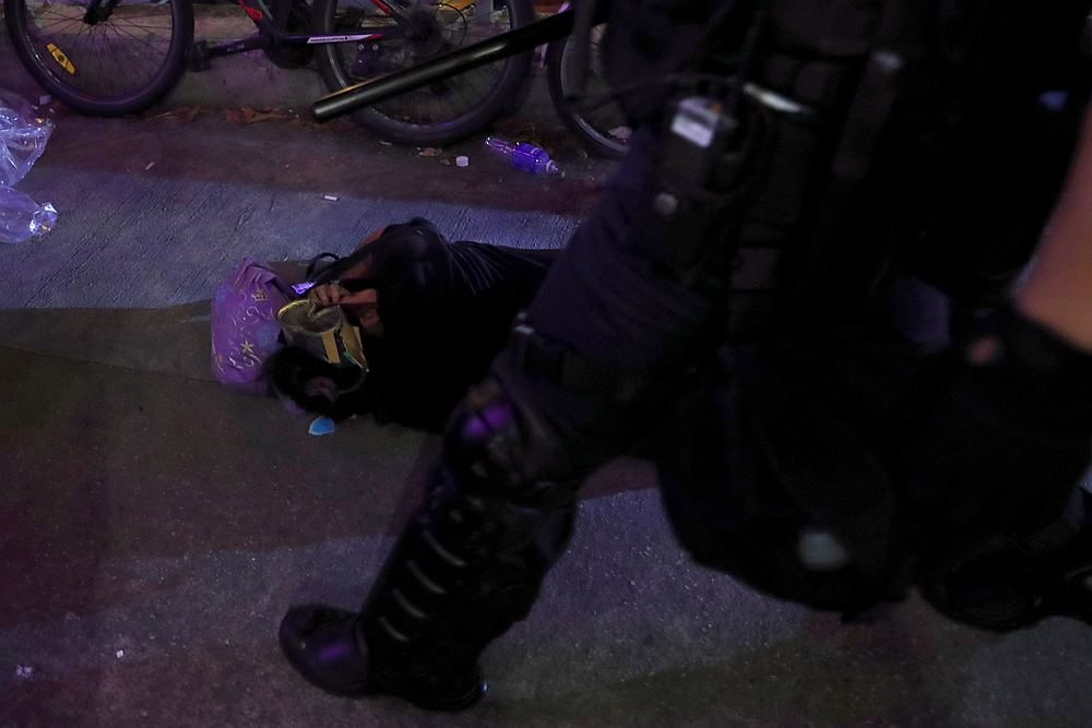 A riot police officer walks past a protester after she was beaten to the ground after a march at Sha Tin District of East New Territories, in Hong Kong July 14, 2019. u00e2u20acu201d Reuters pic