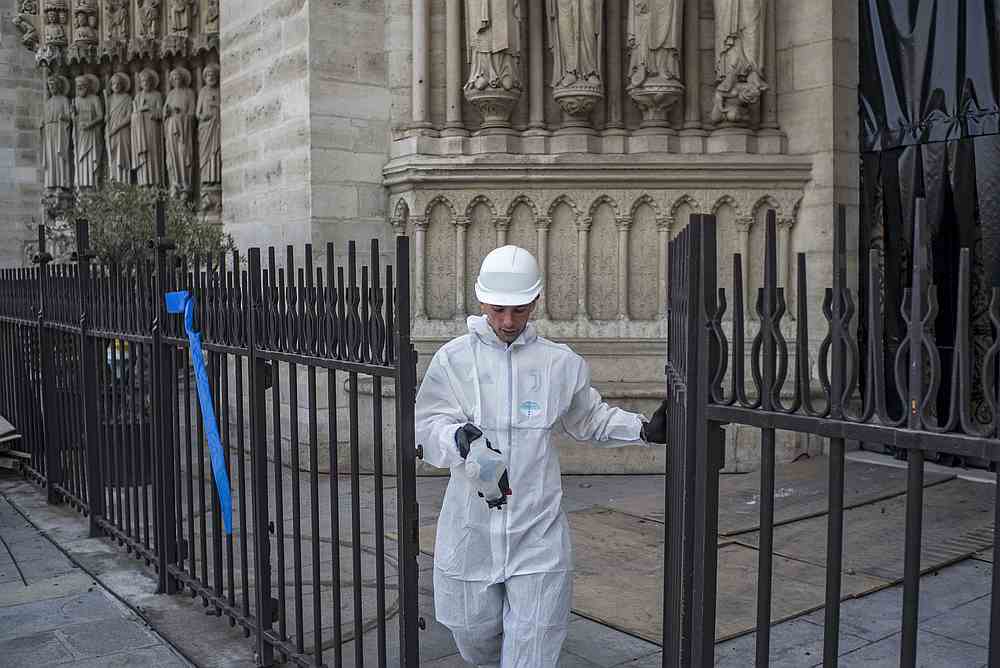 A construction worker walks through a gate at the Notre-Dame de Paris Cathedral during preliminary work on July 24, 2019 in Paris, three months after it was badly damaged by a huge fire last April 15. u00e2u20acu201d AFP pic
