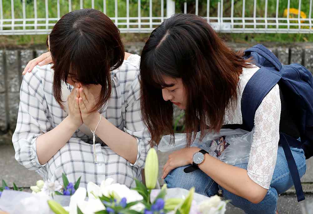 Women pray in front of a row bouquets placed out for victims of the torched Kyoto Animation building in Kyoto, Japan July 20, 2019. u00e2u20acu201d Reuters pic