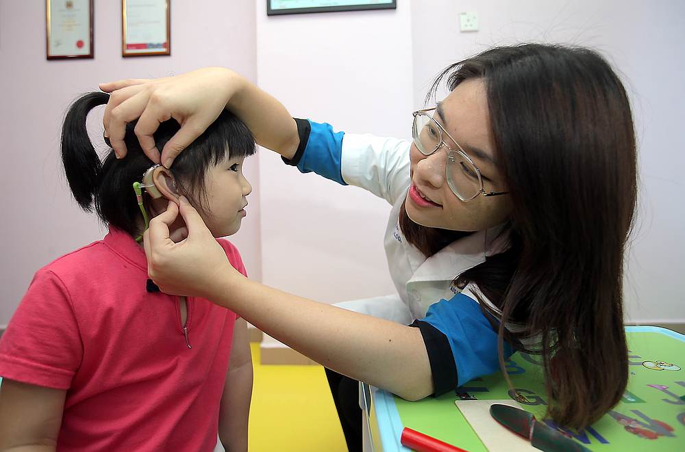 Senior audiologist Sylvia Lee checks on Teoh Wan Men's hearing aid. u00e2u20acu201d Picture by Farhan Najib