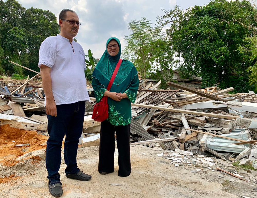 Pakatan Harapan Perling branch head Norman Abdul Hamid (left) and Ainon Musa at the site of where her house stood in Kampung Bakar Batu today after it was accidentally demolished by a contractor hired by a developer July 25, 2019. u00e2u20acu201d Picture by Ben Tan
