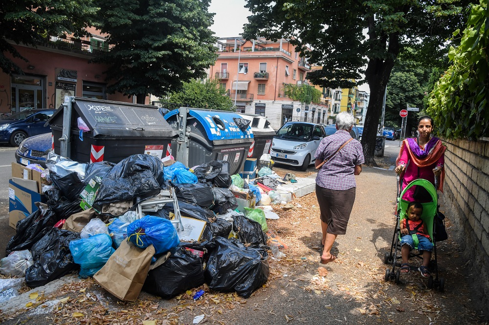 Residents walk past overflowing trash bins on July 10, 2019 in the Centocelle district of Rome. u00e2u20acu201d AFP pic      