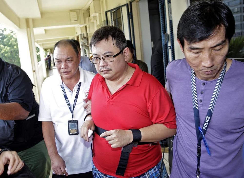 Woodlands murder suspect Teo Ghim Heng (in red) being escorted back to the crime scene on February 10, 2017. u00e2u20acu201d TODAY file pic