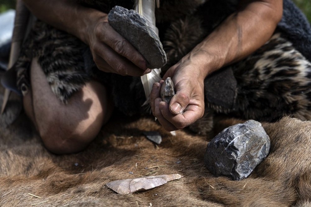 Guido Camia dressed as a Neanderthal Cave man works on a flint ax in a wood near Chianale, in the Italian Alps, near the French border August 7, 2019. u00e2u20acu201d AFP pic