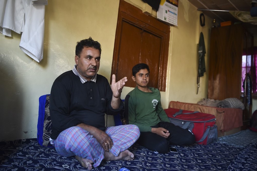 Kashmiri father Mohammad Saleem speaks with AFP as his son Shayan looks on during an interview in their home in Srinagar August 19, 2019. — AFP pic