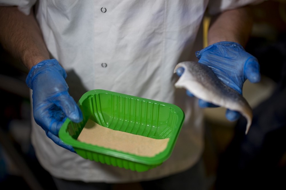 A member of staff uses plastic-free sugarcane packaging to prepare a portion of fish for sale at Budgens supermarket in Belsize Park, north London July 2, 2019. — AFP pic