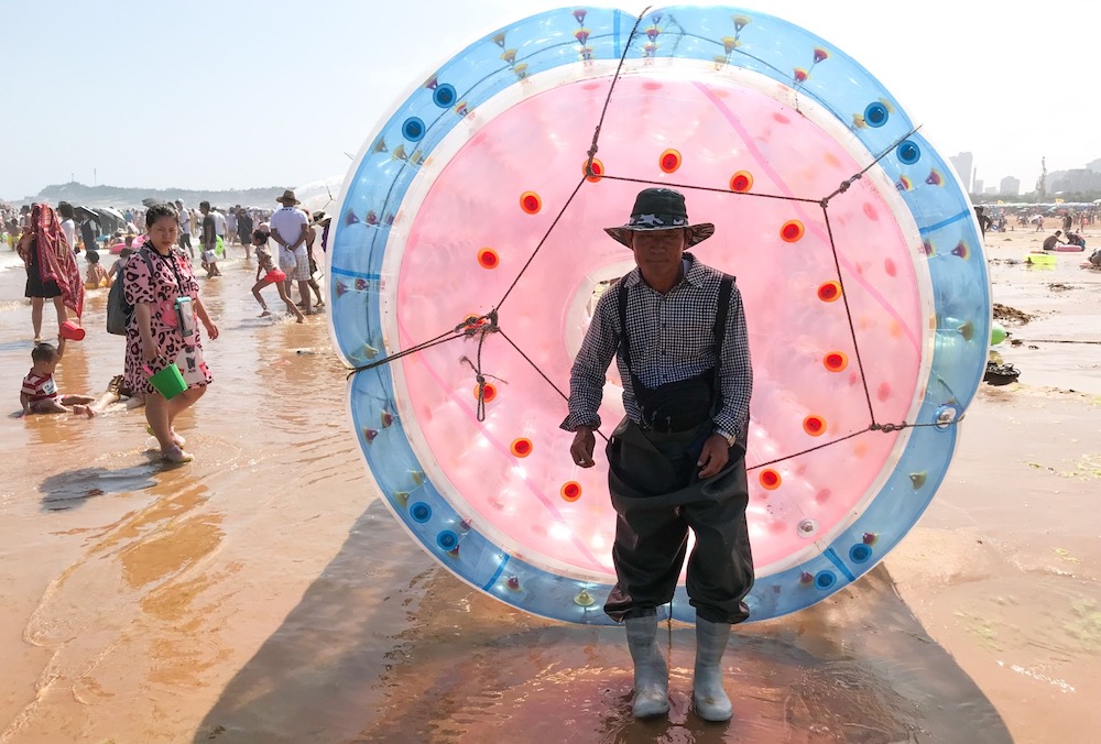 A man waits for paying customers with his inflatable zorb ball on a beach in Qingdao, eastern China's Shandong province August 3, 2019. u00e2u20acu201d AFP pic