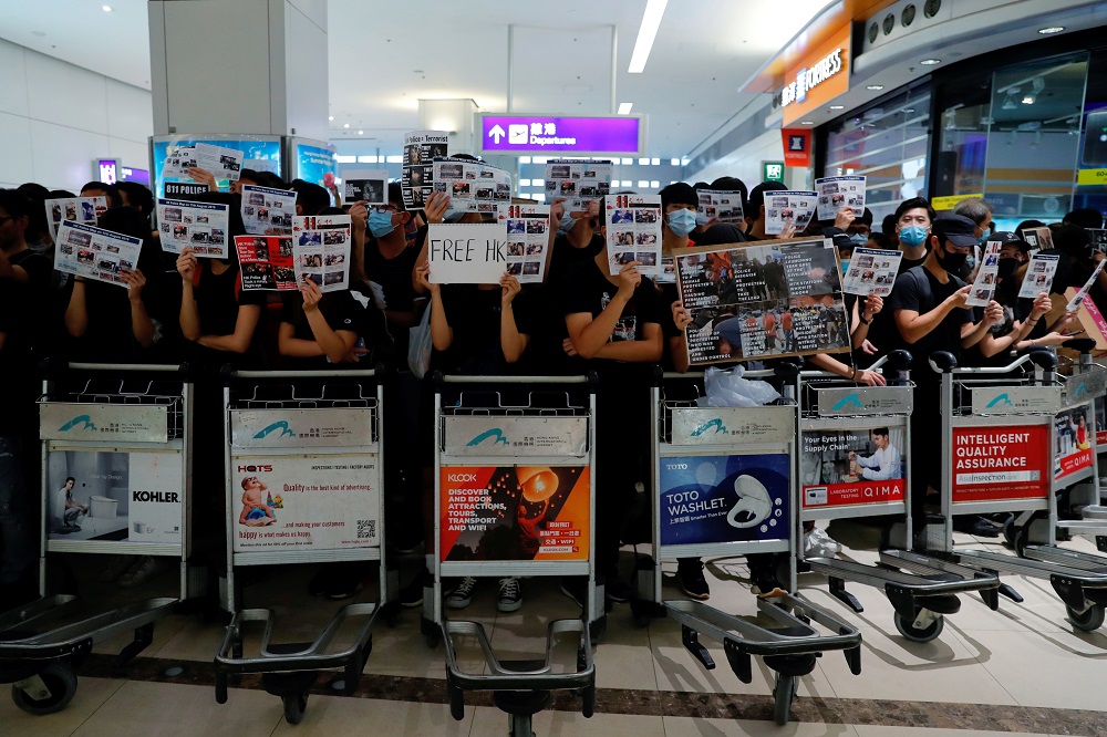 Anti-extradition bill protesters use trolleys to stop passengers from entering the security gates during a mass demonstration after a woman was shot in the eye, at the Hong Kong international airport, in Hong Kong August 13, 2019. — Reuters pic