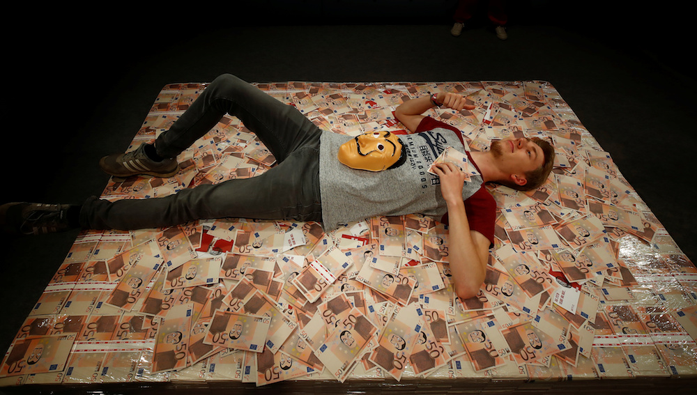 A man gets his picture taken from a roof camera as he lies on a bed of money from the Netflix series ‘Money Heist’ during Gamescom in Cologne August 20, 2019. — Reuters pic