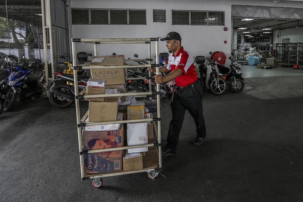 Wheeling the items to his van. — Picture by Firdaus Latif