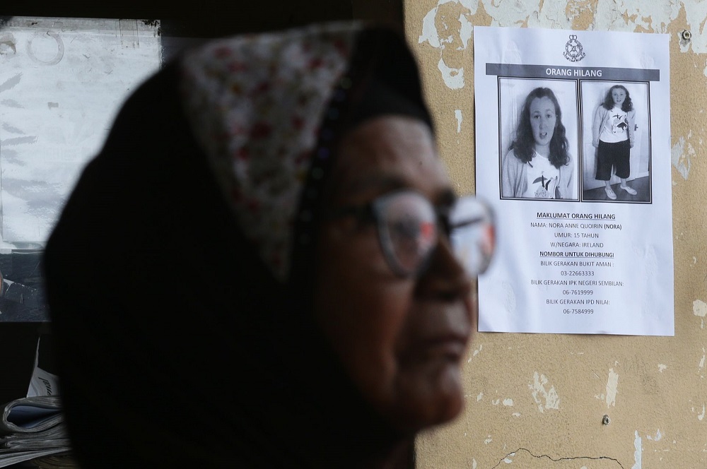 A woman walks past a poster featuring missing Irish teenager Nora Anne Quoirin in Seremban August 10, 2019. — Picture by Ahmad Zamzahuri 
