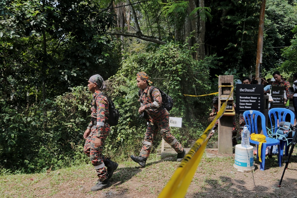 Members of the search team are seen entering an area cordoned by police after the discovery of a body in the jungle near Seremban August 13, 2019. — Picture by Ahmad Zamzahuri