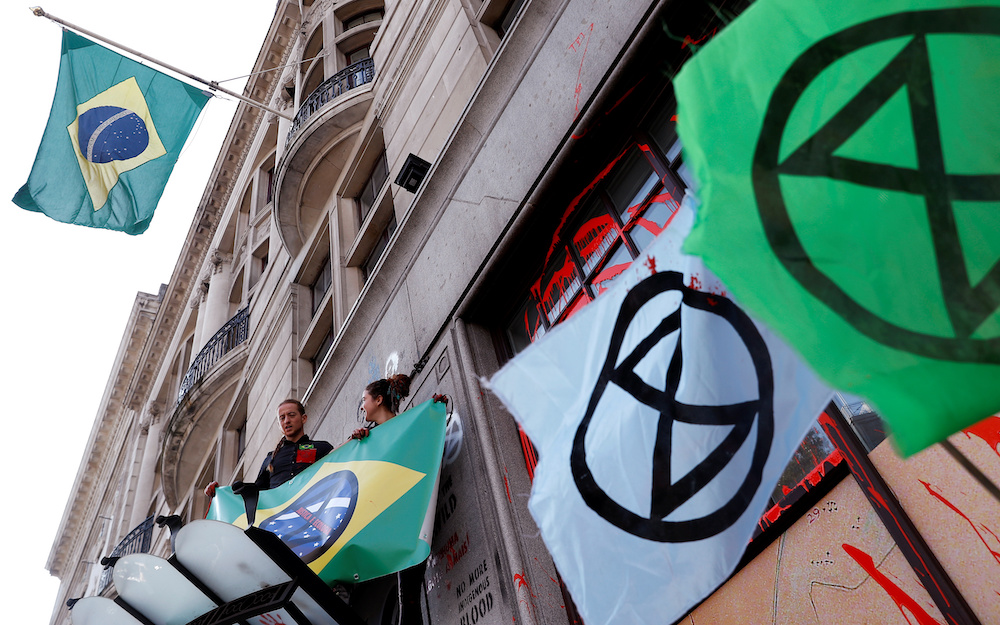 Activists stand on an awning over the embassy's entrance during Extinction Rebellion climate change protest in front of Brazilian Embassy in London August 13, 2019. u00e2u20acu201d Reuters pic