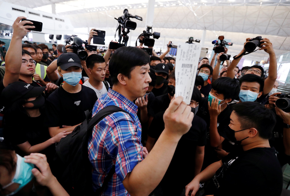 A passenger walks past anti-government protesters as he tries to enter the security gate during a demonstration at Hong Kong Airport August 13, 2019. u00e2u20acu201d Reuters picnn