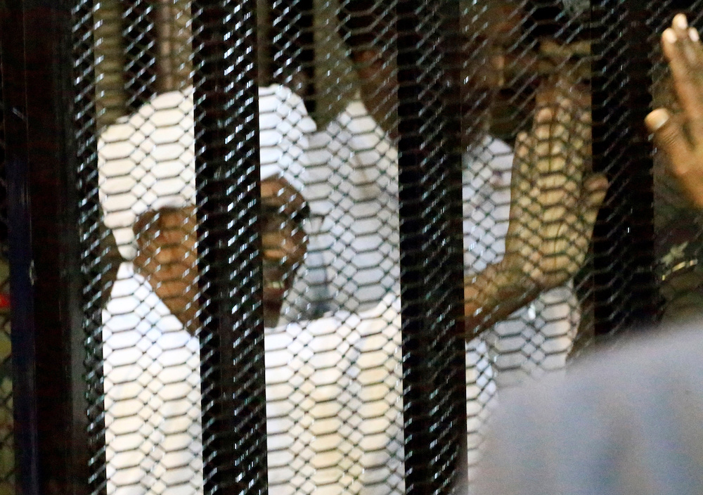 Sudan's former president Omar Hassan al-Bashir waves to relatives and supporters as he is guarded inside a cage at the courthouse where he is facing corruption charges, in Khartoum August 19, 2019. u00e2u20acu201d Reuters picnn