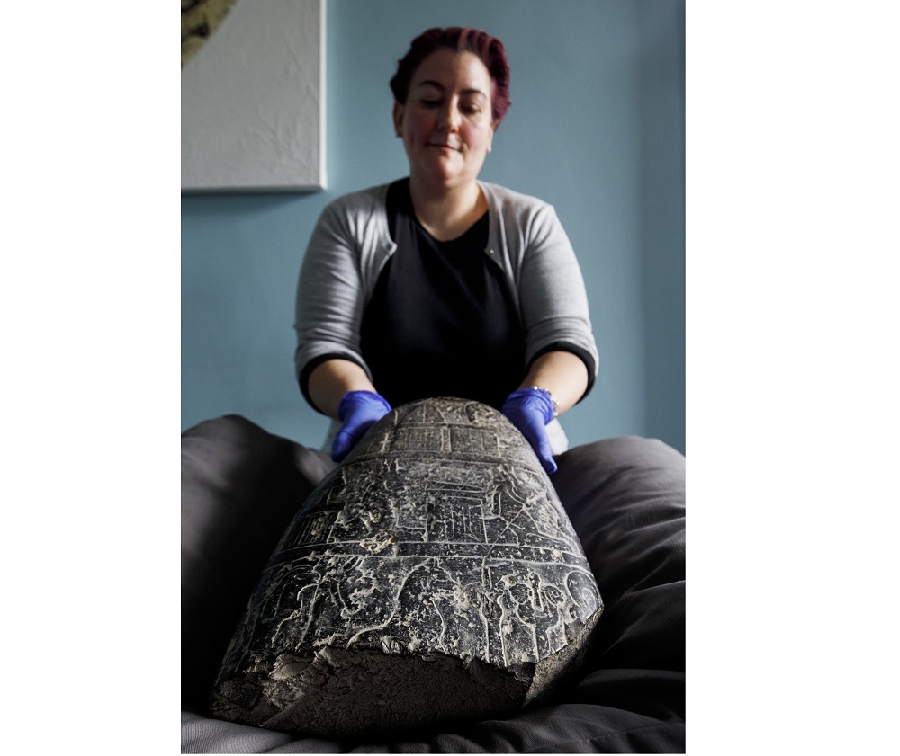 A gallery assistant poses with a Babylonian cuneiform kudurru (boundary stone) which was looted from Iraq on March 19, 2019 at the British museum in London. u00e2u20acu201d AFP pic